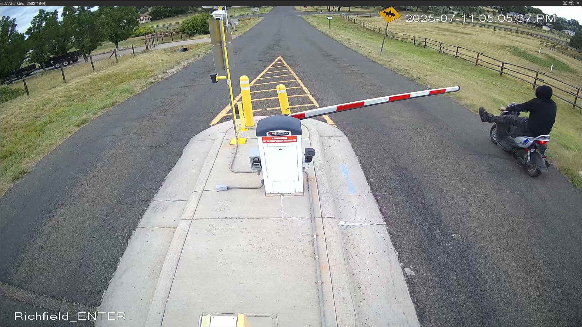 Man driving blue and silver scooter down Richfield having already kicked gate arm.